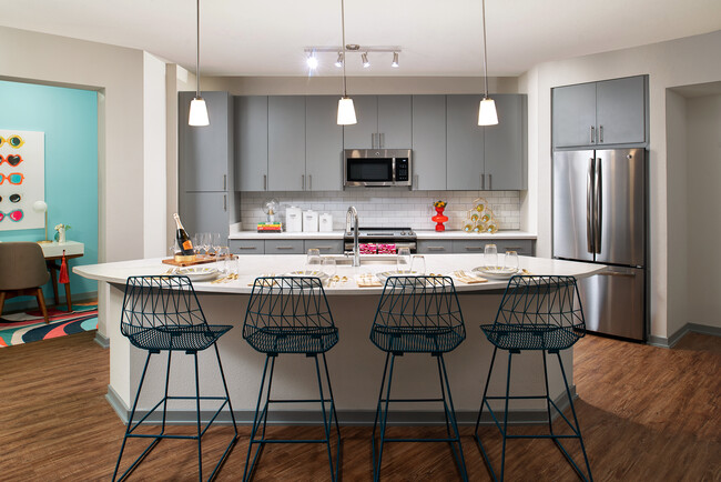 Kitchen with island and stainless steel appliances - The District at Rosemary Apartments