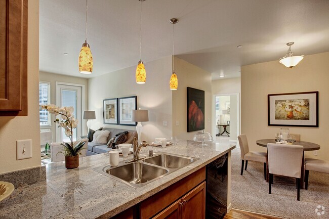 A kitchen with our sleek appliances and stone countertops with a view into the dining area and living room - Solara Rental