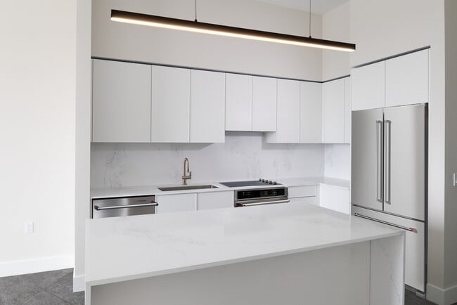 Colección Signature Cocina de apartamento de tres habitaciones con gabinetes blancos, encimera y protector contra salpicaduras de cuarzo de mármol blanco y electrodomésticos de acero inoxidable renovados. - Avalon South Miami Apartamentos