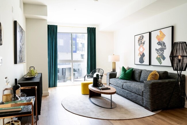 Living room with expansive windows, wood-style plank flooring, and an open layout that creates a bright, comfortable space for relaxing and entertaining.