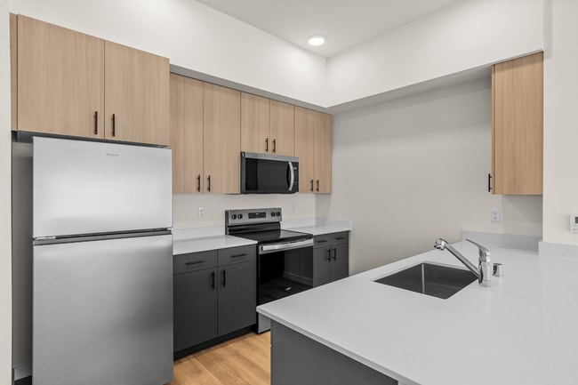 Cook and entertain with ease in a modern kitchen complete with stainless steel appliances, sleek finishes, and ample counter space. - 27 West Apartments