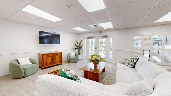 Inviting living room with plush white sectional sofa, elegant wooden furniture, and abundant natural light through large windows. - The Blake at Bradenton