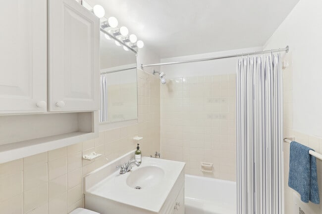Bath with white cabinetry, white laminate countertops, and hard surface flooring