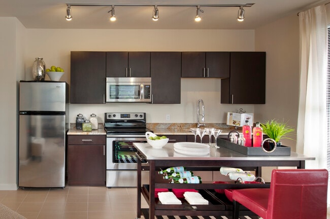 Open concept kitchen with espresso cabinetry, granite countertops, stainless-steel appliances, movable island and hard surface flooring