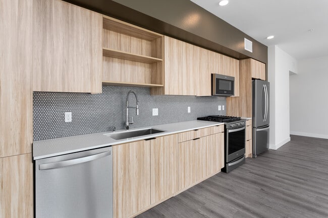 Open concert kitchen with quartz countertops backsplash, stainless steel appliances and hard surface flooring