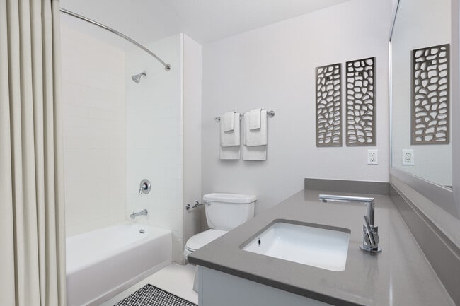 Renovated Phase I bath with quartz countertops and white cabinetry