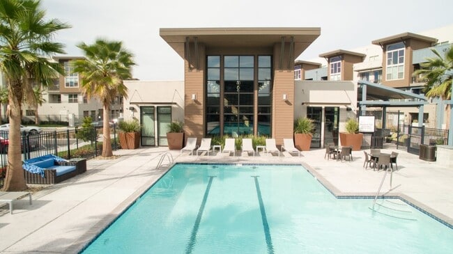 Aspire Apartments Tracy California Luxury Living A large swimming pool in front of a building with palm trees.