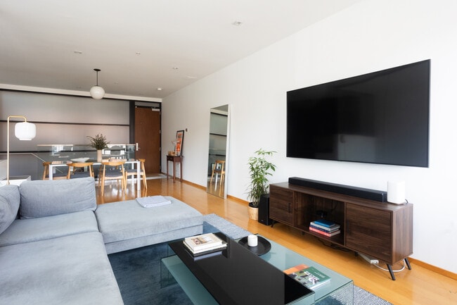 Upon entering, main living space with wall-mounted TV and soundbar. - 2250 11th St NW Unit 103