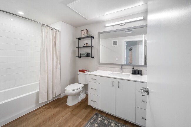 Finish Package I bathroom featuring white cabinetry, white quartz countertops, a framed mirror, and a shower and tub