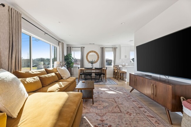 Living room with West Elm furniture, natural sunlight, and large TV flatscreen.