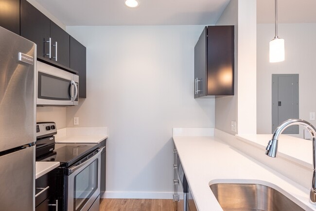 Please note that the countertops may vary by unit. While some feature lighter granite with a beige and brown pattern, others have a more white finish. - Renaissance Station North Apartments