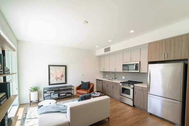 Open-concept home with dual-tone cabinetry, stainless steel appliances, and wood-style plank flooring flowing through a bright, efficient living space.
