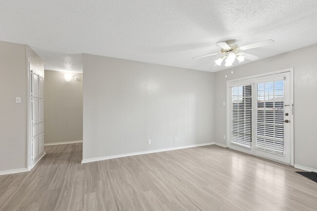A bright living room is shown with vinyl floors and doors opening to private patio.