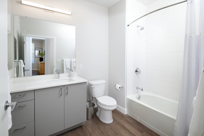 Modern baths with light grey cabinetry, white quartz countertop, and hard surface flooring
