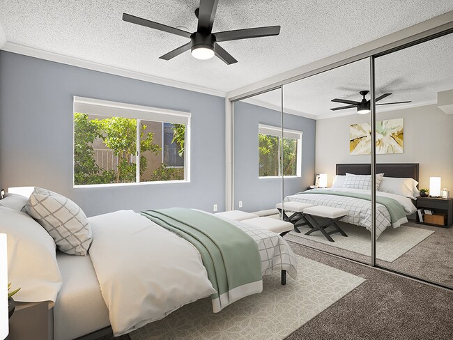 Carpeted bedroom with ceiling fan and large mirrored closets. - Tilden II Apartments