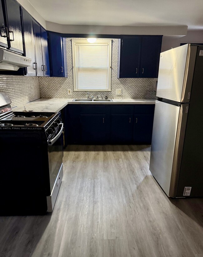 Newly renovated kitchen with blue cabinets, backsplash, and granite countertops - 20212 Mada Ave Casa