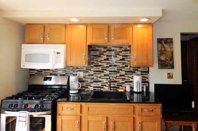 Kitchen with tiled backsplash, gas range and microwave - 2820 NY-28 House Unit #2