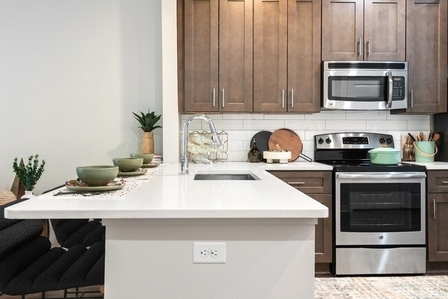 Cocina moderna con electrodomésticos de acero inoxidable y gabinetes de madera oscura. - Lamar Union