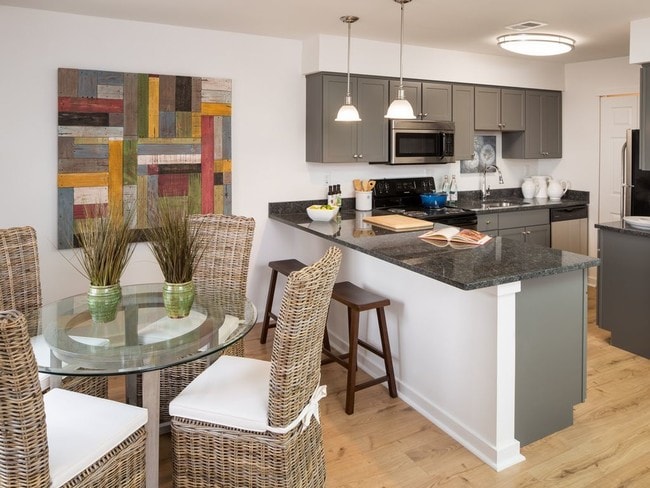 Apartment kitchen with stainless steel, granite countertops, and dark cabinetry