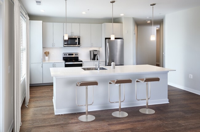 Design Collection I Kitchen with light grey cabinetry, white quartz countertops, pendant lighting, and hard surface flooring