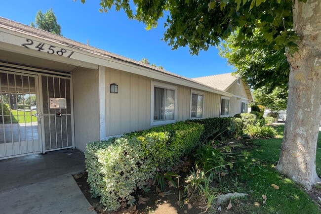 Árboles maduros y jardines cerca de la entrada principal de Eucalyptus Apartments en Moreno Valley, California. - Eucalyptus Apartments