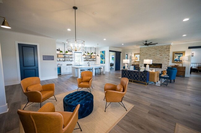 Kitchenette inside the Clubhouse with expansive island that offers bar seating and a microwave. Looking onto the living room area with ample seating, and fireplace.