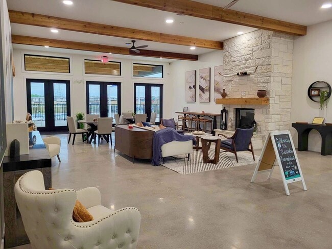 Clubhouse featuring a cozy fireplace, lounge chairs, café tables, and a welcome sign on an easel near the entry