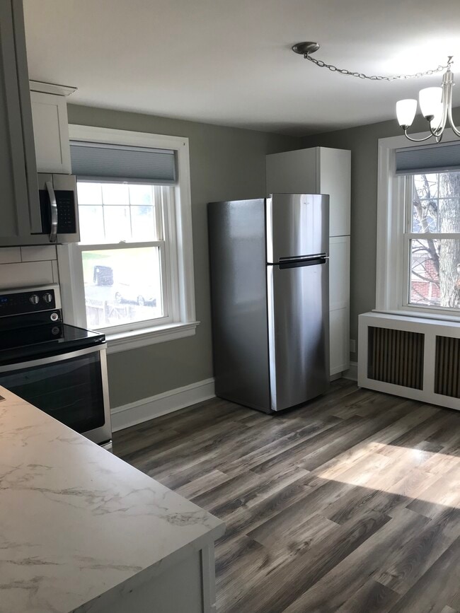 Cocina recién reformada con armarios blancos, salpicadero de azulejos tipo metro y electrodomésticos de acero inoxidable. - 430 Main St Unidad B