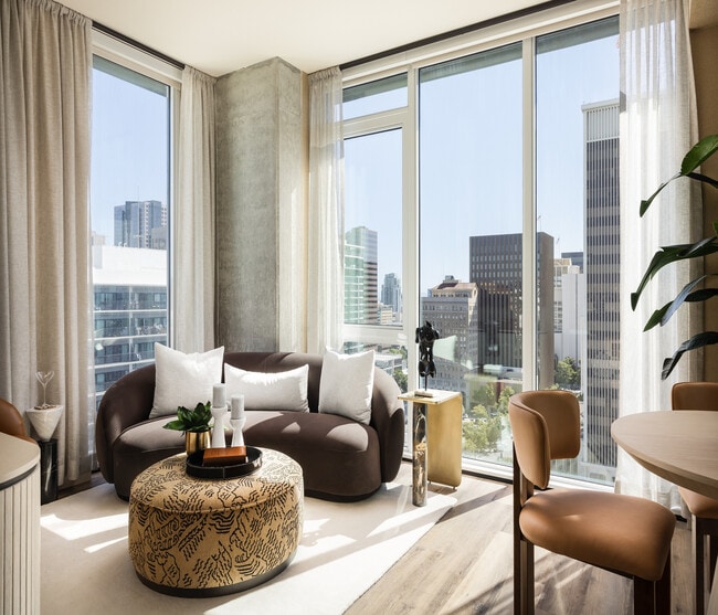 Modern living room with panoramic city views, featuring stylish furniture and abundant natural light.