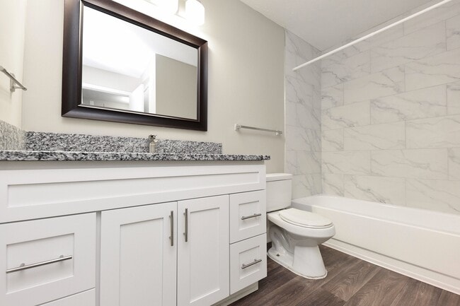 Bright bathroom with granite counters and bathtub with marble backsplash