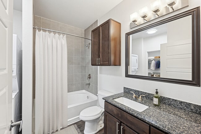 Refreshed Finishes bath with espresso cabinetry, speckled granite countertops, and hard surface flooring