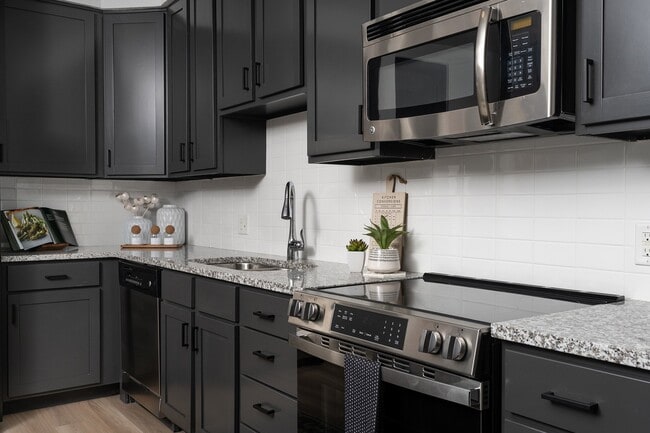 Stainless steel appliances with modern white tile backsplash in kitchen
