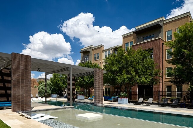 Piscina estilo resort con zona para tomar el sol y terraza.