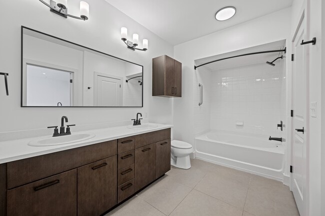 Vanity counter space between the sinks, with a tub across the room.