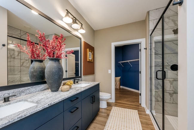 Elevated bathrooms with double vanities and Carrera-inspired tiled showers