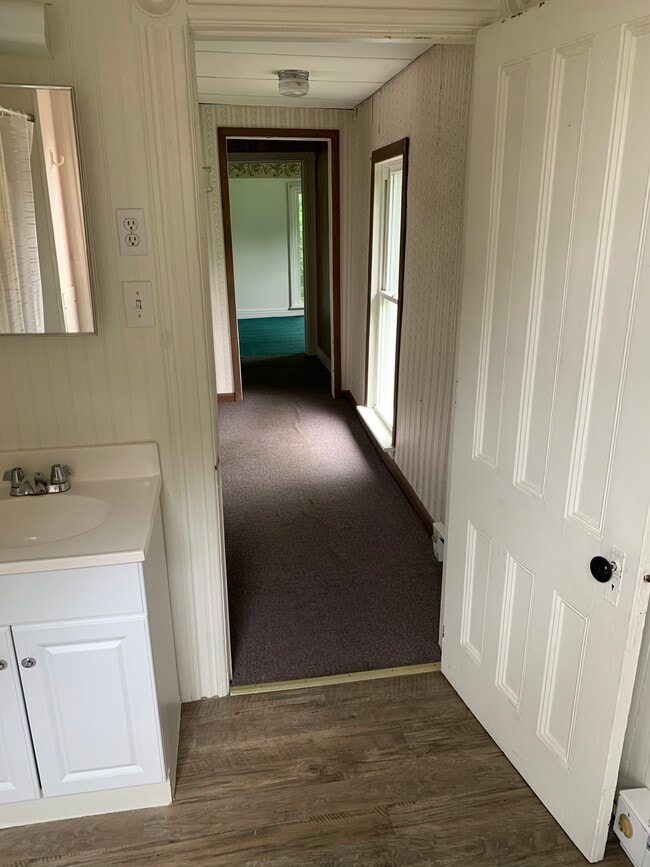 Baño con vista al pasillo hacia la cocina a la izquierda y el dormitorio 1 al final. - 7614 Collins St Unidad #2 upstairs