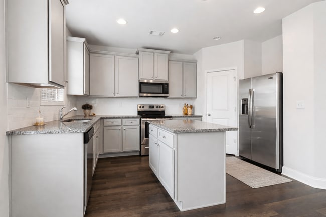 Spacious kitchen with an island, ample storage, stainless steel appliances and view into the living room.