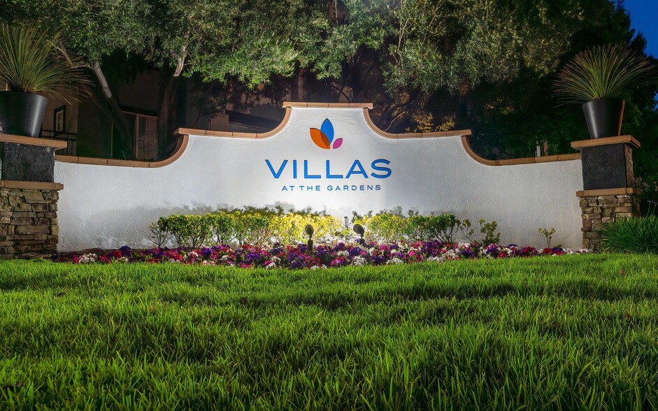 Villas at the Gardens Illuminated Entry Sign with Lush Lawn and Colorful Flowers