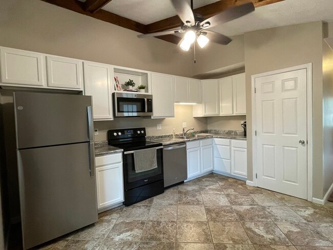 Cocina con techo abovedado, ventilador de techo y electrodomésticos que incluyen lavavajillas y microondas de acero inoxidable. - 1277 Tallberry Dr