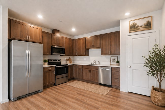 Elegant kitchen with modern stainless steel appliances, warm wood cabinetry, and inviting plank floors.