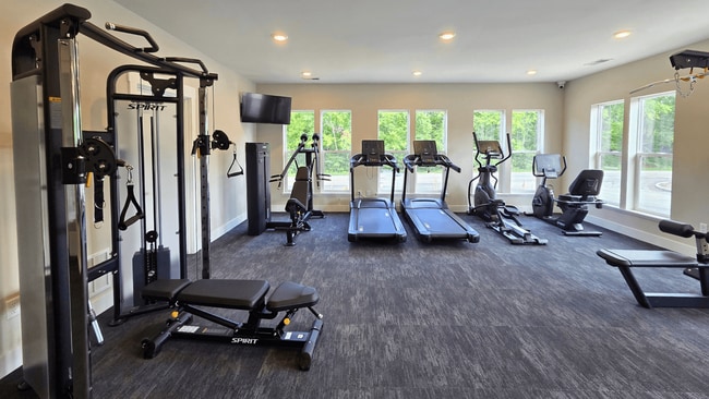 A spacious gym with a variety of equipment including treadmills, stationary bike, weights, and benches, located at the clubhouse at Greenwood Commons Apartments in Delaware, OH. - Greenwood Commons Apartments