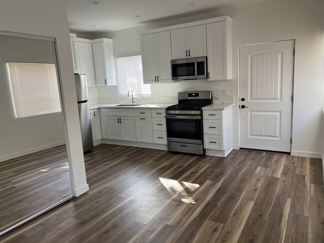 Kitchen and entry door seen from the living area. - 1026 Simmons Ave Apartments Unit 1026 half