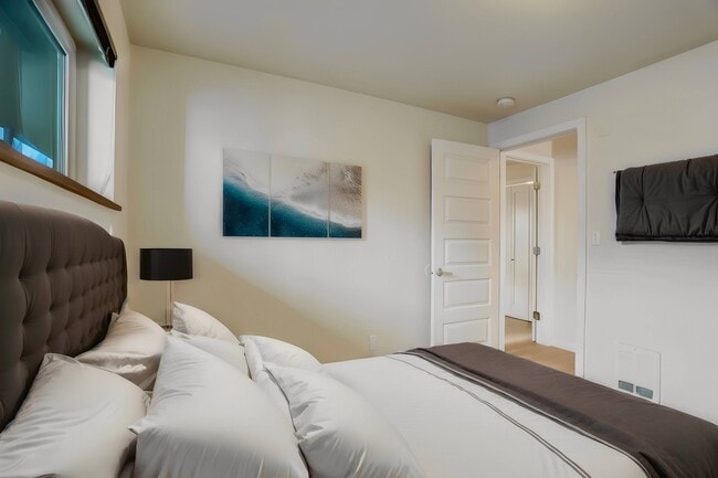 A cozy bedroom featuring a comfortable bed, natural light from the window, and a door leading to an adjacent room, offering a warm and inviting atmosphere. - Alaska 45