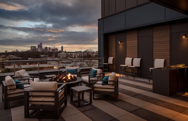 Outdoor Lounge with Fire Feature Overlooking Evening Cityscape - NoDa Flats