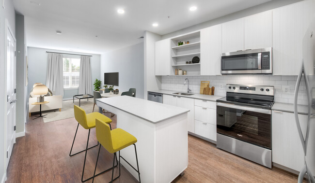 Kitchen with quartz stone countertops and white cabinetry with tile backsplash on hard surface flooring - Kanso Twinbrook Apartments