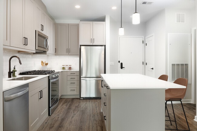 Upgrade Collection kitchen with stainless steel appliances, quartz countertops, tile backsplash, grey cabinetry, and hard-surface flooring