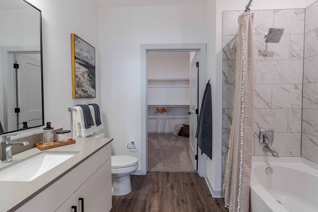 The spa-inspired bathroom connects to a generous walk-in closet and features a soaking tub with marble-style tile and a sleek quartz vanity.