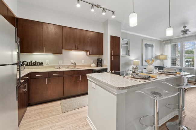 Kitchen with dark cabinetry, beige speckled granite countertops, stainless steel appliances, and hard surface flooring