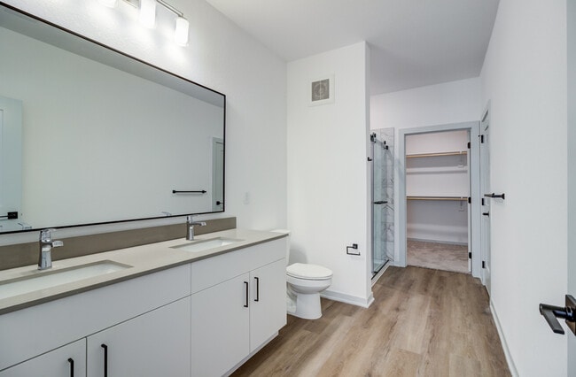 A double vanity with dual sinks, a large black-framed mirror, and a walk-in shower connect directly to the walk-in closet for a seamless, hotel-inspired suite experience. - Garrett Forum