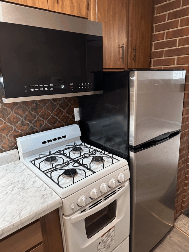 Kitchenette with fridge, four burners gas stove and microwave with exhaust hood. - 834 S Walnut St Unit 834R S. Walnut